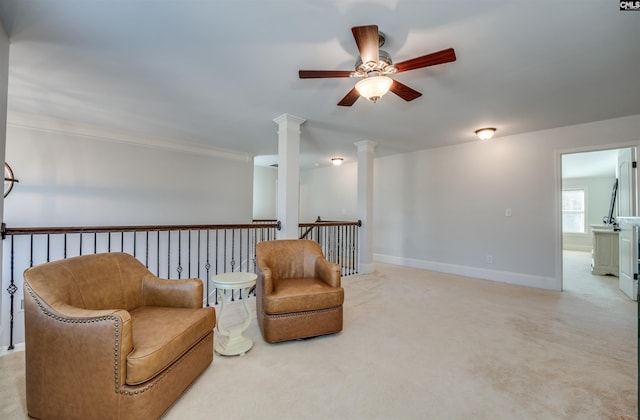 sitting room with decorative columns, ceiling fan, crown molding, and light colored carpet