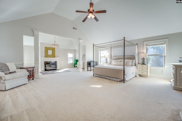 bedroom featuring high vaulted ceiling, light colored carpet, ornate columns, and ceiling fan