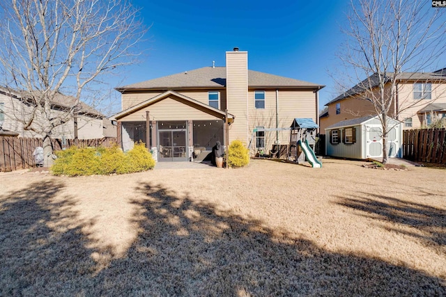 back of property with a playground, a sunroom, and a shed