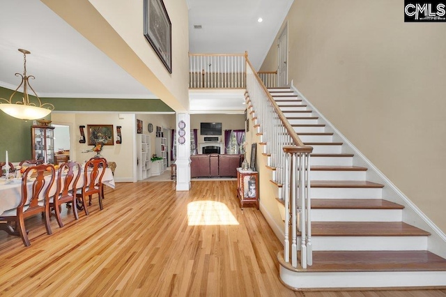 foyer entrance featuring french doors, ornamental molding, a towering ceiling, and light hardwood / wood-style flooring