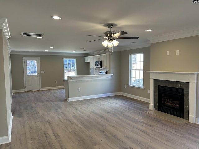 unfurnished living room with light hardwood / wood-style flooring, ceiling fan, crown molding, and a tiled fireplace