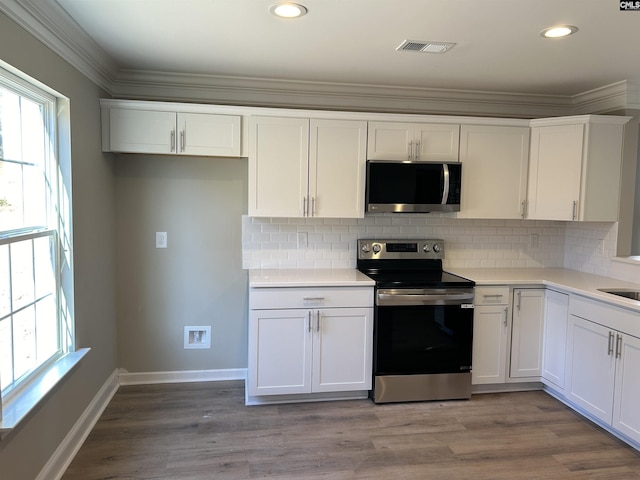 kitchen featuring decorative backsplash, white cabinetry, and stainless steel appliances