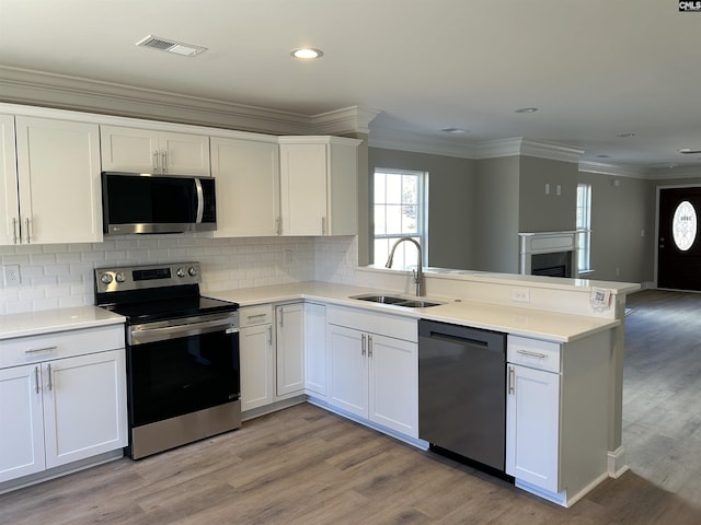 kitchen featuring white cabinetry, kitchen peninsula, sink, and appliances with stainless steel finishes