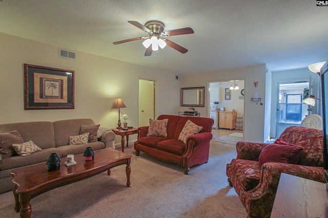 living room with ceiling fan, light carpet, and a textured ceiling