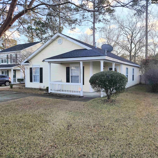 ranch-style home featuring covered porch and a front yard