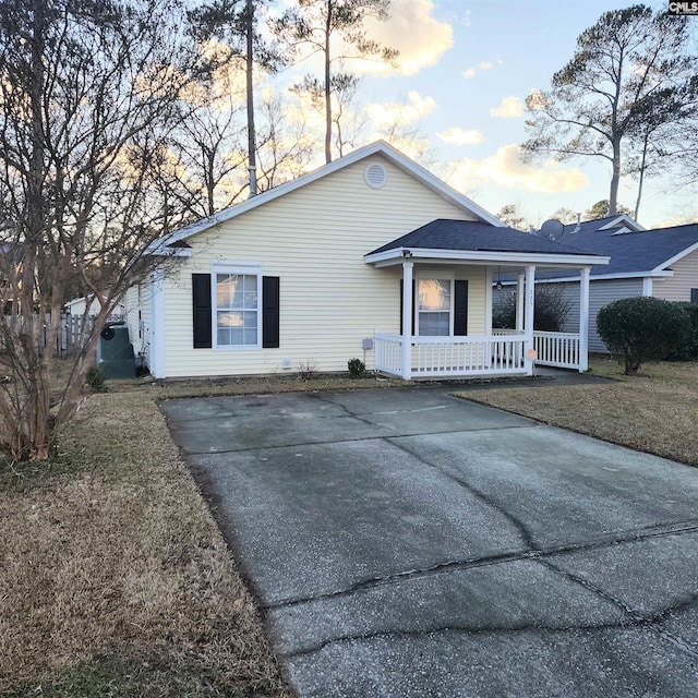 ranch-style home featuring covered porch and a yard