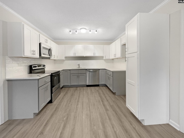 kitchen featuring appliances with stainless steel finishes, gray cabinetry, a textured ceiling, sink, and light hardwood / wood-style floors