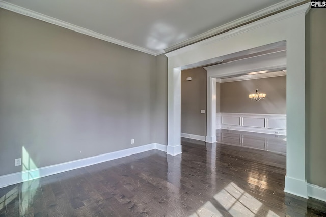 empty room with dark hardwood / wood-style floors, crown molding, and a chandelier