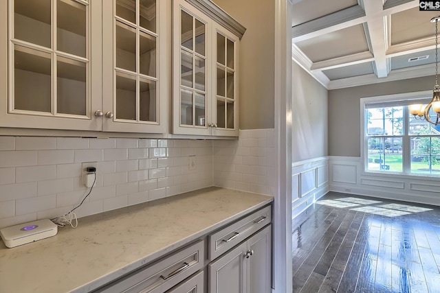 bar featuring an inviting chandelier, coffered ceiling, hanging light fixtures, beam ceiling, and light stone counters