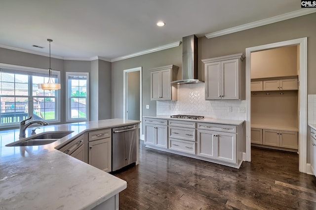 kitchen featuring backsplash, wall chimney exhaust hood, stainless steel appliances, sink, and hanging light fixtures