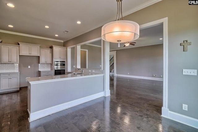 kitchen featuring pendant lighting, white cabinetry, double oven, and tasteful backsplash