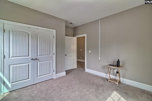 unfurnished bedroom with light carpet and a closet