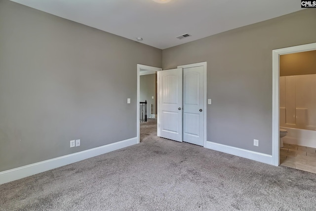 unfurnished bedroom featuring ensuite bath and light colored carpet