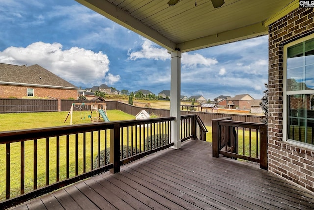 wooden deck featuring a playground, ceiling fan, and a lawn