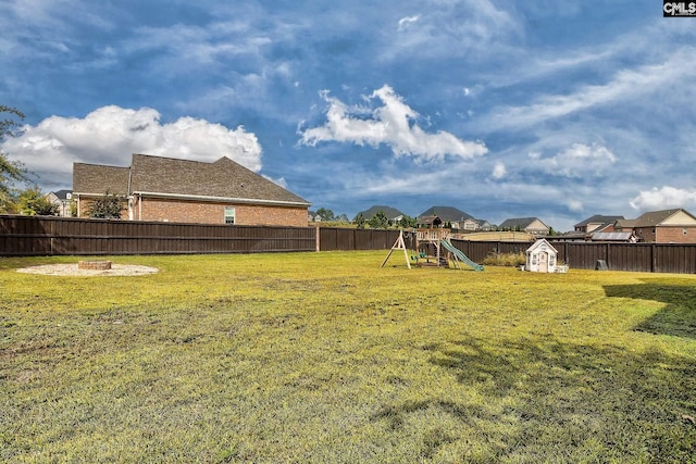 view of yard with a playground, a shed, and a fire pit