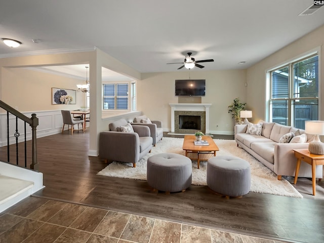 living room with crown molding, dark wood-type flooring, and ceiling fan with notable chandelier