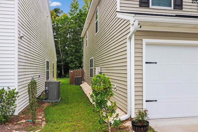 view of home's exterior with cooling unit, a garage, and a yard