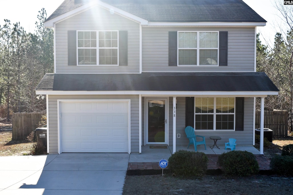 front of property with covered porch, a garage, and central air condition unit