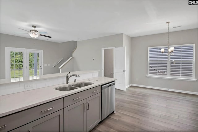 kitchen featuring ceiling fan with notable chandelier, pendant lighting, sink, gray cabinets, and stainless steel dishwasher