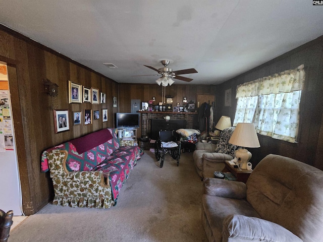 carpeted living room featuring ceiling fan, a fireplace, and wooden walls