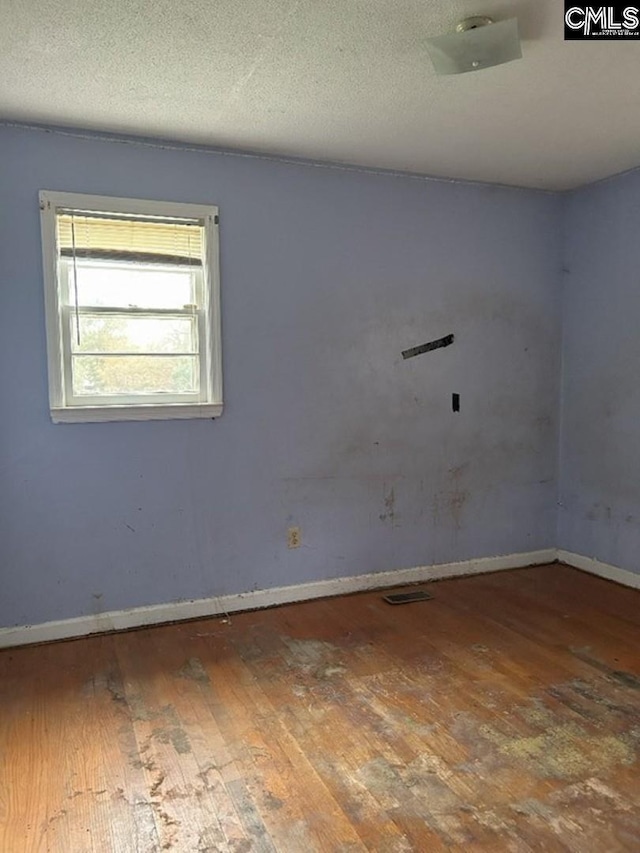 empty room with hardwood / wood-style flooring and a textured ceiling