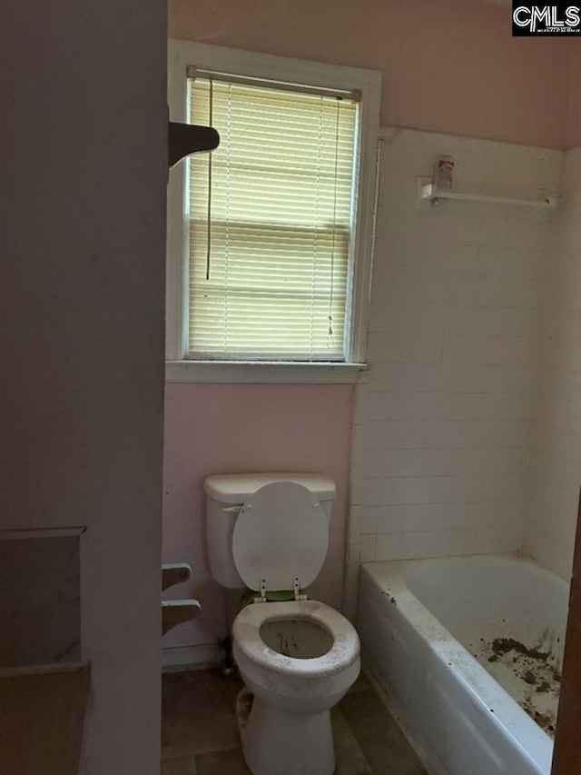 bathroom with tile patterned floors, toilet, a bath, and a wealth of natural light