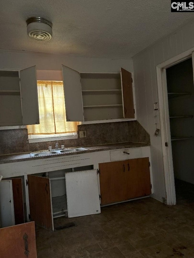 kitchen featuring a textured ceiling, backsplash, and sink