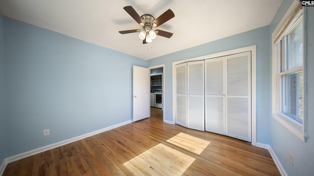 unfurnished bedroom featuring ceiling fan, light hardwood / wood-style flooring, washer / clothes dryer, and a closet