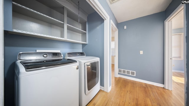 laundry area with separate washer and dryer, light hardwood / wood-style floors, and a textured ceiling