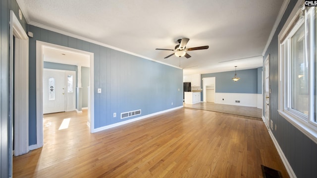 unfurnished living room featuring hardwood / wood-style flooring, ceiling fan, and crown molding