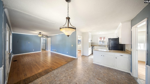 kitchen with ceiling fan, sink, black refrigerator, white cabinets, and hardwood / wood-style flooring