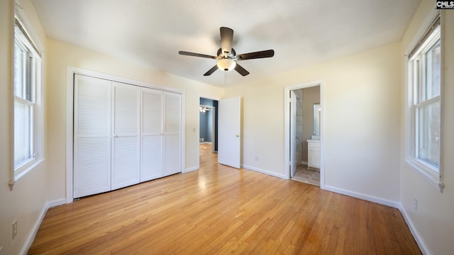 unfurnished bedroom with a closet, ensuite bathroom, light hardwood / wood-style flooring, and ceiling fan