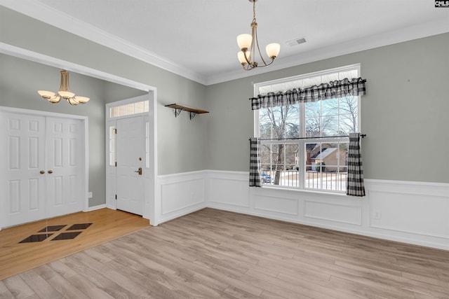 interior space featuring ornamental molding, a notable chandelier, and light wood-type flooring