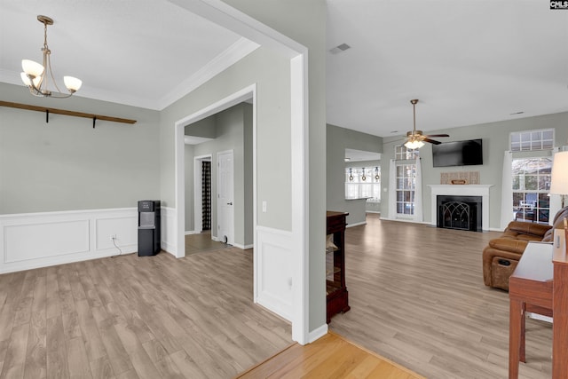 living room featuring ceiling fan with notable chandelier, light hardwood / wood-style floors, and crown molding