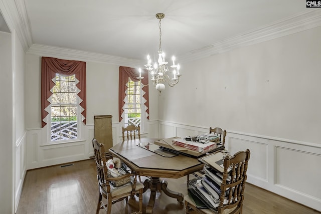 dining area featuring hardwood / wood-style flooring, ornamental molding, and an inviting chandelier