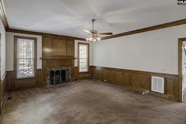 unfurnished living room with a fireplace, carpet, ceiling fan, and ornamental molding