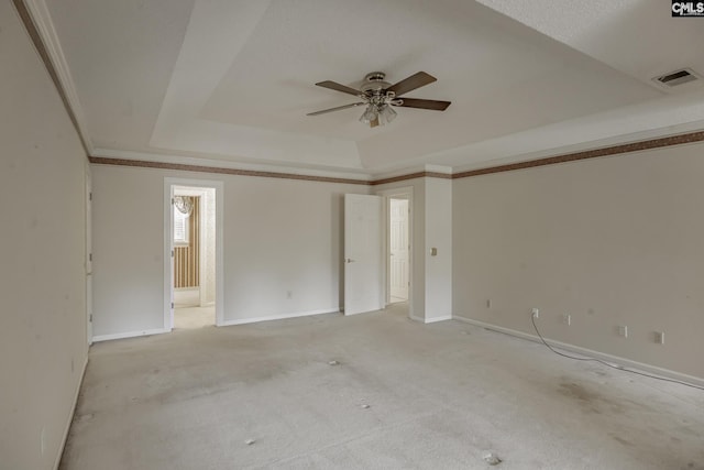 spare room with a tray ceiling, ceiling fan, crown molding, and light colored carpet