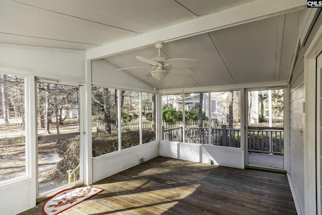 unfurnished sunroom featuring lofted ceiling with beams, ceiling fan, and plenty of natural light