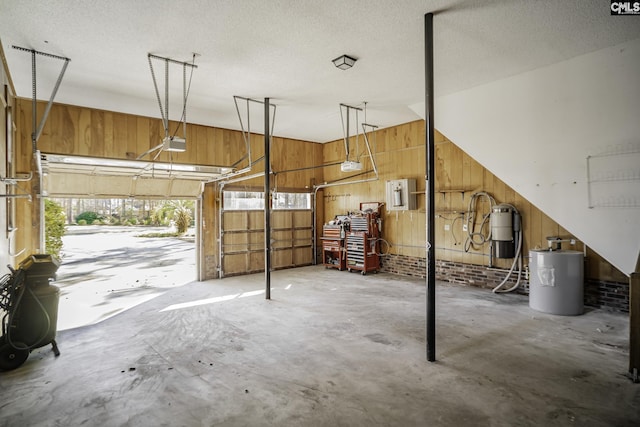 garage with a garage door opener, wooden walls, and water heater