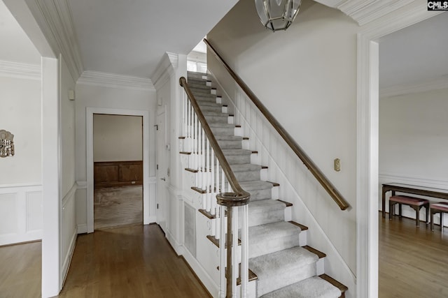 staircase with hardwood / wood-style flooring and crown molding