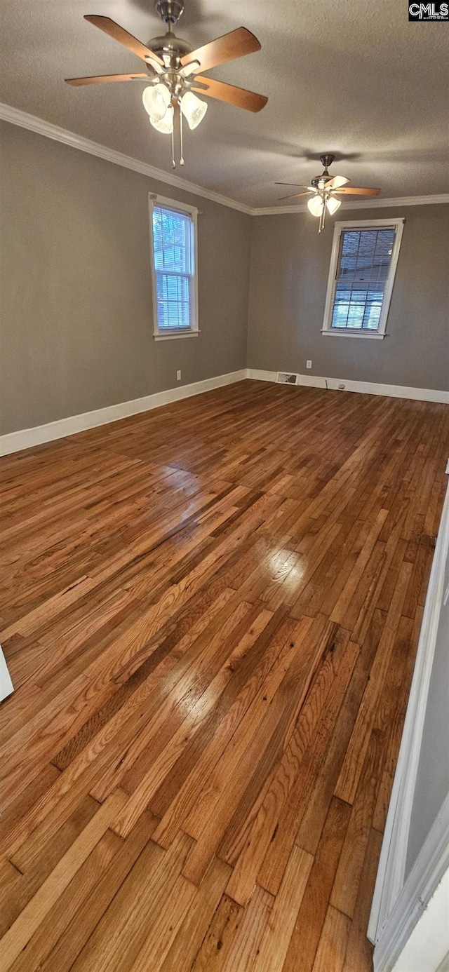 spare room with crown molding, wood-type flooring, and a textured ceiling