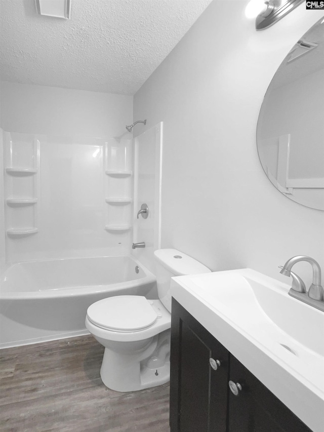 full bathroom featuring vanity, bathtub / shower combination, toilet, a textured ceiling, and wood-type flooring