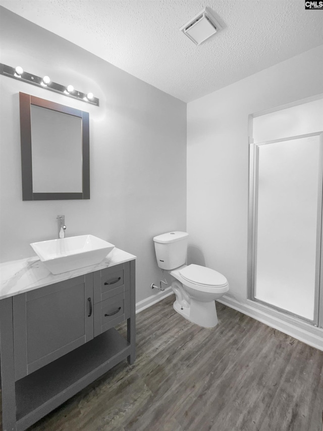 bathroom with vanity, wood-type flooring, a textured ceiling, and toilet