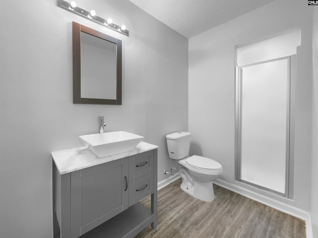 bathroom featuring hardwood / wood-style floors, an enclosed shower, a textured ceiling, toilet, and vanity