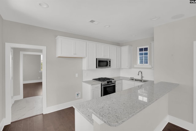 kitchen with white cabinets, sink, light stone countertops, and stainless steel appliances