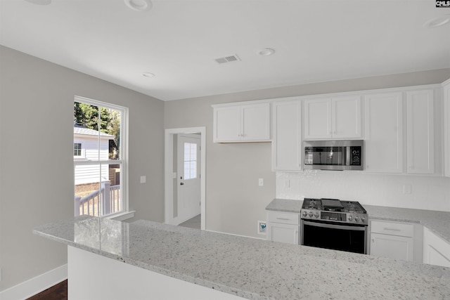 kitchen featuring dark hardwood / wood-style floors, white cabinetry, stainless steel appliances, and light stone counters