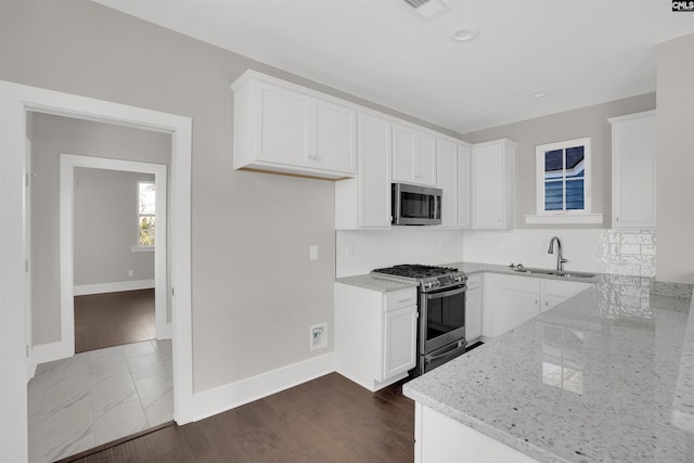 kitchen featuring light stone countertops, white cabinetry, sink, and appliances with stainless steel finishes