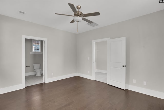 unfurnished bedroom with ensuite bathroom, ceiling fan, a spacious closet, dark hardwood / wood-style floors, and a closet