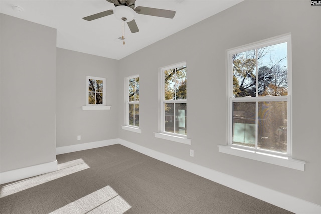 spare room with ceiling fan and dark colored carpet