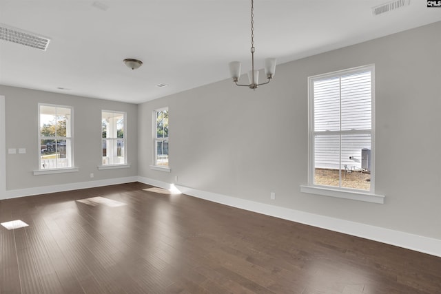 unfurnished room with dark hardwood / wood-style floors and an inviting chandelier